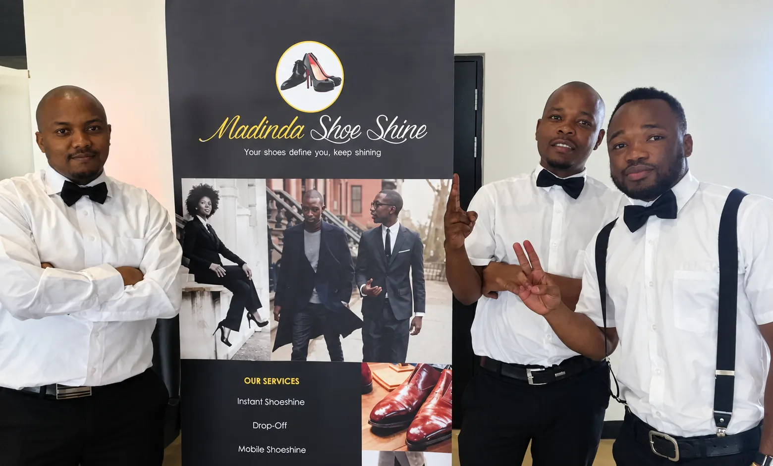 Three Madinda Shoe Shine specialists in white shirts and black bow ties stand beside a branded Madinda Shoe Shine banner.